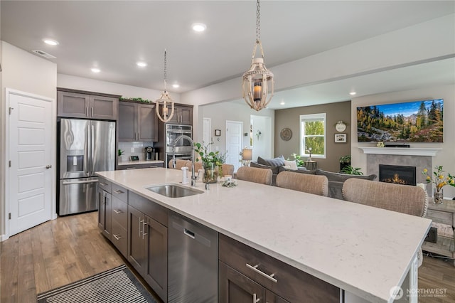 1448 101st Ave SE, Lake Stevens, WA 98258 - kitchen featuring stainless steel appliances, dark brown cabinetry, open floor plan, a tiled fireplace, and recessed lighting