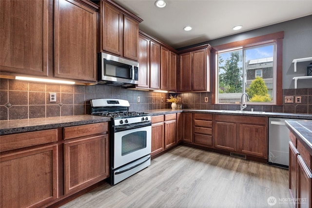 15204 Kayla St SE, Yelm, WA 98597 - kitchen with stainless steel appliances, decorative backsplash, light wood finished floors, recessed lighting, and dark stone countertops