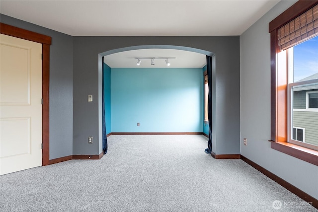 15204 Kayla St SE, Yelm, WA 98597 - empty room with arched walkways, carpet flooring, and rail lighting