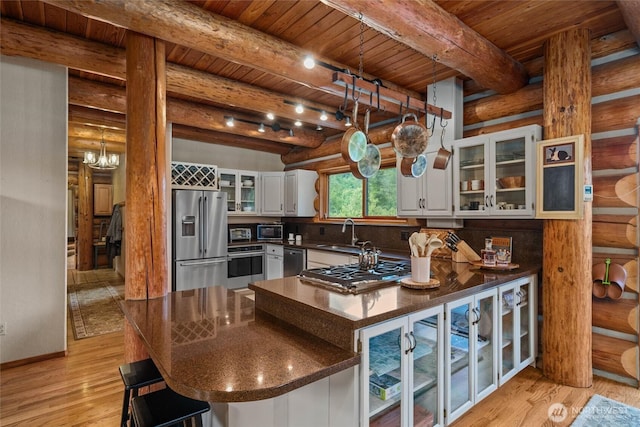 3130 S Bay Vista Dr, Sedro Woolley, WA 98284 - kitchen with stainless steel appliances, dark countertops, a wood ceiling with exposed beams, log walls, and a peninsula