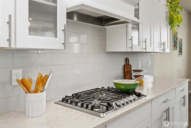 25613 204th Pl SE, Covington, WA 98042 - kitchen with custom exhaust hood, stainless steel gas cooktop, white cabinets, glass insert cabinets, and decorative backsplash