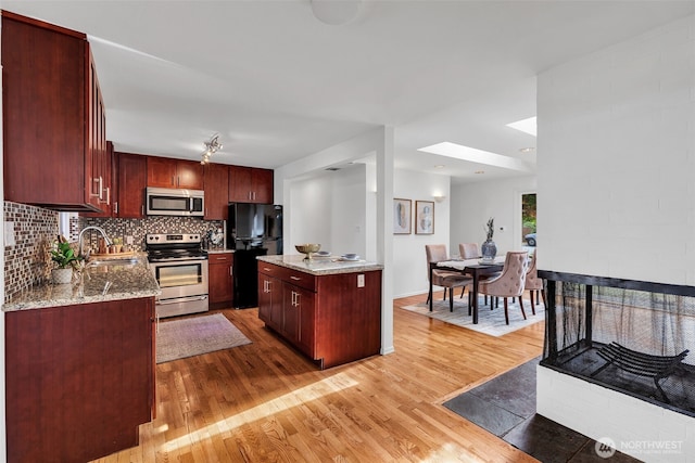 18256 45th Ave S, Seatac, WA 98188 - kitchen with stainless steel appliances, light wood finished floors, reddish brown cabinets, and light stone counters