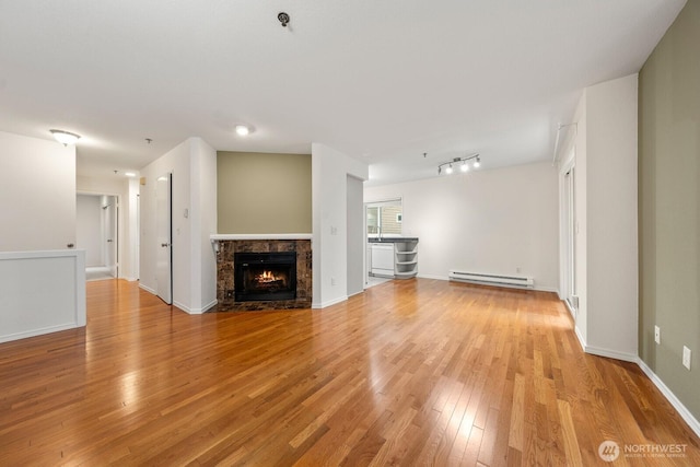 17424 NE 88th Pl Unit B24, Redmond, WA 98052 - unfurnished living room featuring a baseboard heating unit, light wood-style flooring, and a stone fireplace