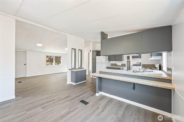 138 Trestle View Ln, Dryden, WA 98821 - kitchen with freestanding refrigerator, gray cabinets, light wood-style flooring, light countertops, and a peninsula