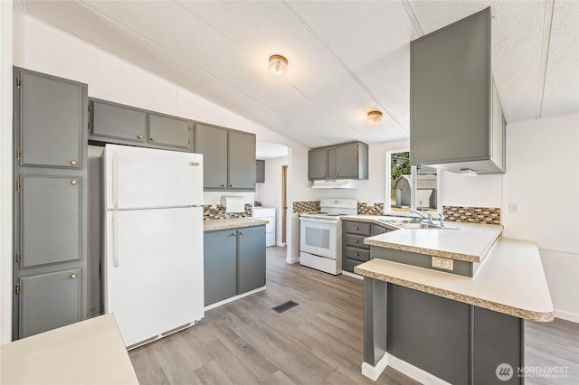 138 Trestle View Ln, Dryden, WA 98821 - kitchen with white appliances, gray cabinets, a peninsula, vaulted ceiling, and light countertops