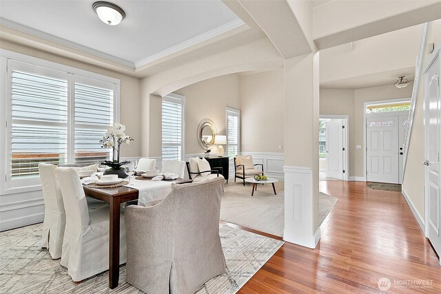 9225 225th Ave E, Buckley, WA 98321 - dining room featuring arched walkways, wood finished floors, plenty of natural light, a wainscoted wall, and a decorative wall