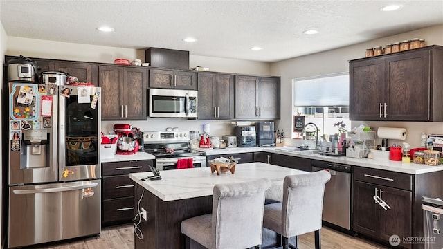 920 E Mt Adams St, Othello, WA 99344 - kitchen featuring appliances with stainless steel finishes, dark brown cabinetry, light wood finished floors, a center island, and recessed lighting