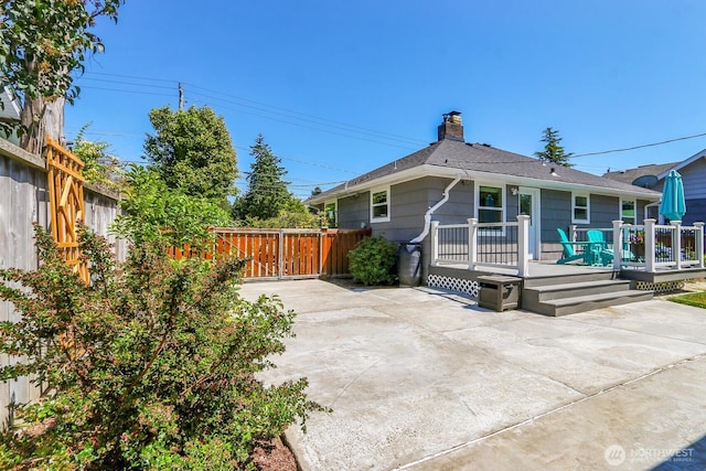 11729 Phinney Ave N, Seattle, WA 98133 - back of property with a patio, a wooden deck, a chimney, and a shingled roof