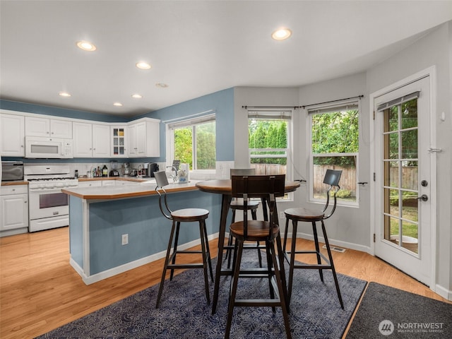 9114 80th Ave SW, Lakewood, WA 98498 - kitchen with white appliances, white cabinets, recessed lighting, light wood-type flooring, and glass insert cabinets