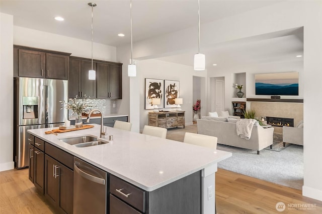 11306 143rd Dr NE, Lake Stevens, WA 98258 - kitchen with appliances with stainless steel finishes, light wood finished floors, dark brown cabinetry, hanging light fixtures, and open floor plan
