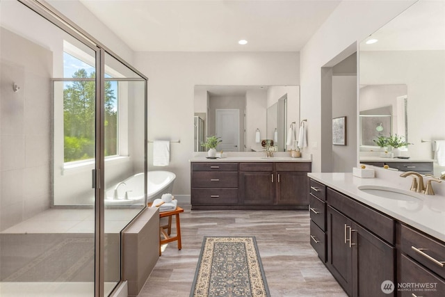 11306 143rd Dr NE, Lake Stevens, WA 98258 - bathroom featuring two vanities, a freestanding tub, wood finished floors, a shower stall, and recessed lighting
