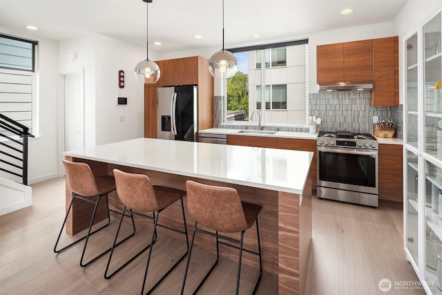 8314 14th Ave NW # B, Seattle, WA 98117 - kitchen featuring appliances with stainless steel finishes, brown cabinets, modern cabinets, decorative backsplash, and recessed lighting