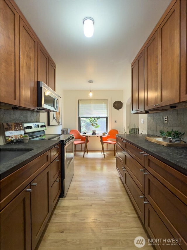 2328 10th Ave E Unit 102, Seattle, WA 98102 - kitchen with stainless steel appliances, decorative backsplash, and light wood-style flooring