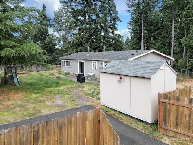 29704 68th Ave S, Roy, WA 98580 - back of house with a shingled roof, a storage unit, a fenced backyard, and view of scattered trees
