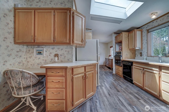 1754 NE Mesford Rd Unit 71, Poulsbo, WA 98370 - kitchen with wallpapered walls, black appliances, a skylight, wood finished floors, and light countertops