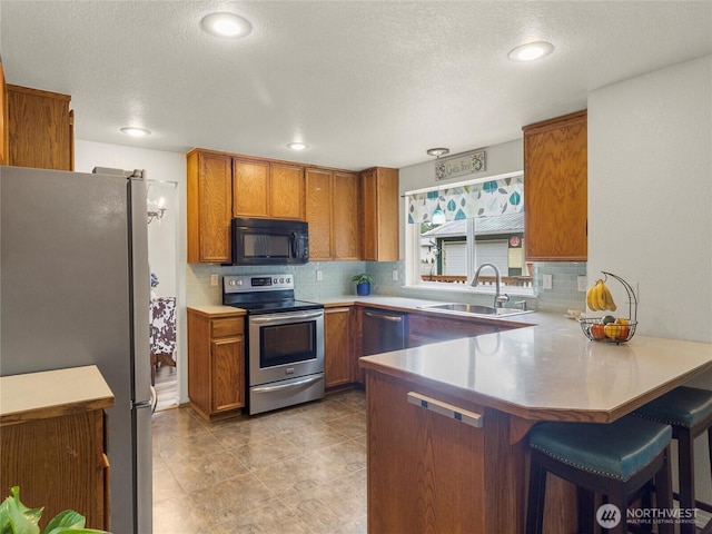 4607 225th Street Ct E, Spanaway, WA 98387 - kitchen featuring appliances with stainless steel finishes, brown cabinets, a peninsula, decorative backsplash, and recessed lighting