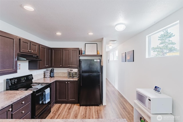 7543 Wooldridge Dr, Blaine, WA 98230 - kitchen with black appliances, under cabinet range hood, dark brown cabinetry, light wood-style floors, and light stone countertops