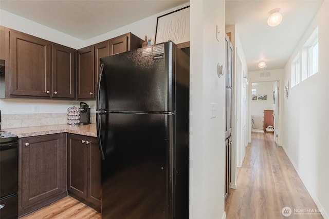 7543 Wooldridge Dr, Blaine, WA 98230 - kitchen with freestanding refrigerator, stove, dark brown cabinetry, and light wood-type flooring