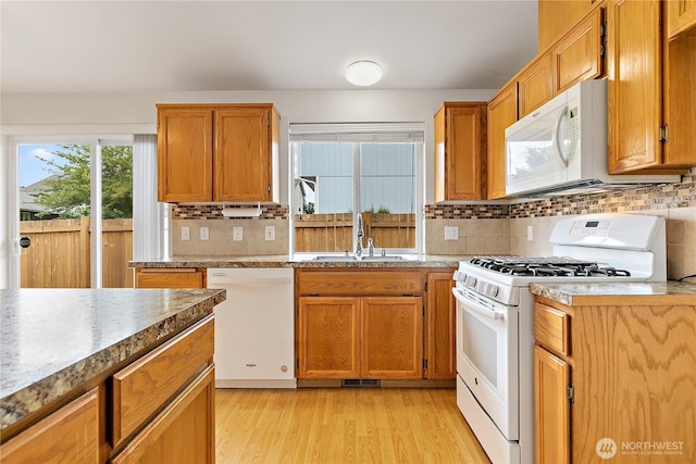8803 136th St E, Puyallup, WA 98373 - kitchen with white appliances, light wood-style flooring, tasteful backsplash, and brown cabinets
