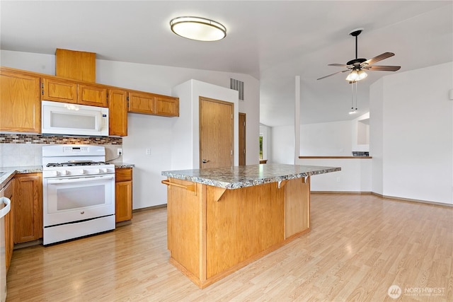 8803 136th St E, Puyallup, WA 98373 - kitchen with white appliances, light wood finished floors, decorative backsplash, brown cabinets, and ceiling fan