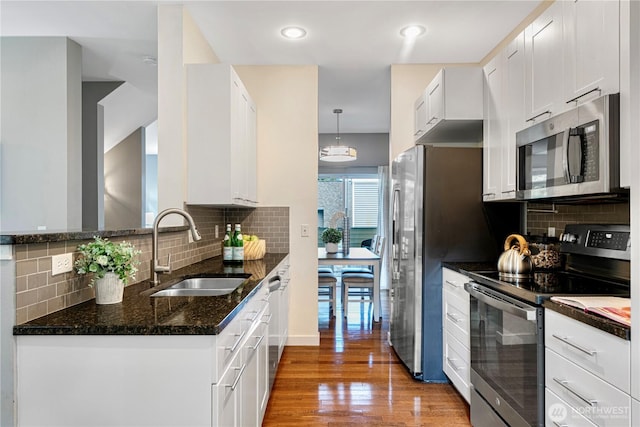 6707 SE Cougar Mountain Way Unit 2, Bellevue, WA 98006 - kitchen with stainless steel appliances, dark stone counters, wood finished floors, decorative backsplash, and recessed lighting