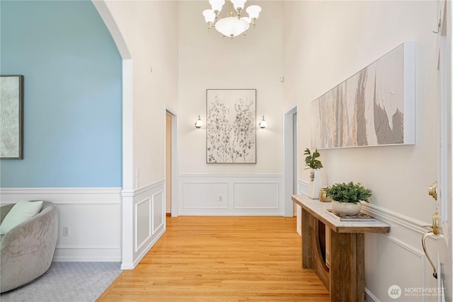1912 243rd Pl SE, Bothell, WA 98021 - hall featuring arched walkways, light wood-style floors, a chandelier, a wainscoted wall, and a towering ceiling