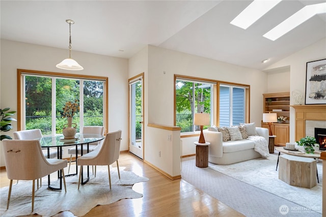 1912 243rd Pl SE, Bothell, WA 98021 - dining room featuring light wood-type flooring, plenty of natural light, a tile fireplace, lofted ceiling, and a skylight