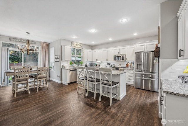 8316 230th Street Ct E, Graham, WA 98338 - kitchen with stainless steel appliances, dark wood-style flooring, white cabinetry, a chandelier, and a kitchen breakfast bar