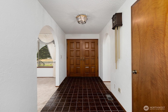 9802 124th St E, Puyallup, WA 98373 - doorway to outside featuring arched walkways, a textured ceiling, carpet, and a textured wall