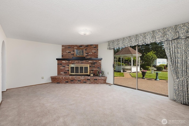 9802 124th St E, Puyallup, WA 98373 - unfurnished living room featuring carpet flooring, a textured ceiling, a brick fireplace, and arched walkways