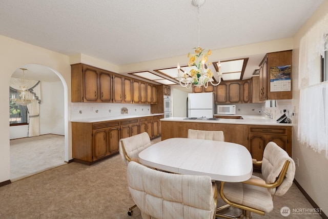 9802 124th St E, Puyallup, WA 98373 - kitchen with a chandelier, white appliances, and light colored carpet