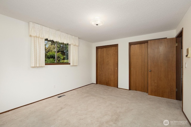 9802 124th St E, Puyallup, WA 98373 - unfurnished bedroom with two closets, carpet, and a textured ceiling