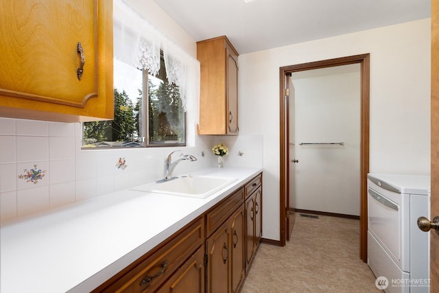 9802 124th St E, Puyallup, WA 98373 - kitchen featuring washer / clothes dryer, decorative backsplash, light countertops, brown cabinetry, and light floors