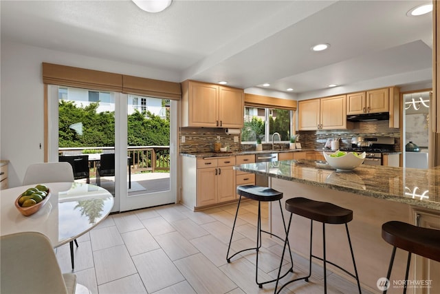 6210 105th Ave NE, Kirkland, WA 98033 - kitchen featuring stainless steel gas stove, a breakfast bar area, decorative backsplash, light brown cabinetry, and recessed lighting