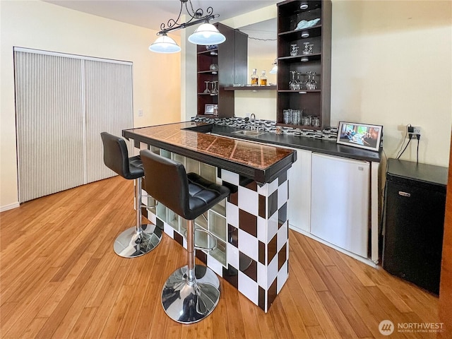 7806 Birch Bay Dr Unit 501, Blaine, WA 98230 - bar area featuring light wood finished floors, decorative light fixtures, and fridge