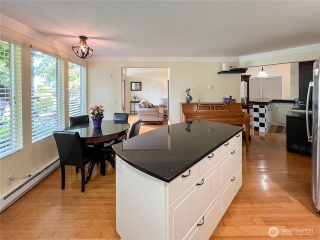 7806 Birch Bay Dr Unit 501, Blaine, WA 98230 - kitchen featuring a baseboard heating unit, white cabinets, light wood-style floors, dark countertops, and a kitchen island