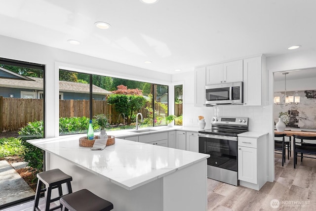 17805 NE 29th St, Redmond, WA 98052 - kitchen with stainless steel appliances, light stone countertops, a breakfast bar, backsplash, and recessed lighting