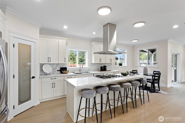 15006 Old Manor Way, Lynnwood, WA 98087 - kitchen with island exhaust hood, stainless steel appliances, crown molding, light wood-style floors, and decorative backsplash