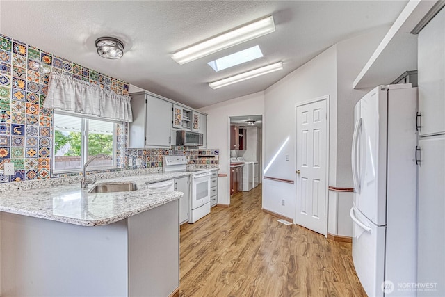 530 Sunday Dr, East Wenatchee, WA 98802 - kitchen with white appliances, vaulted ceiling, light wood-style flooring, tasteful backsplash, and a peninsula