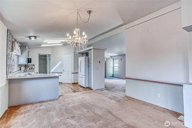 530 Sunday Dr, East Wenatchee, WA 98802 - kitchen with freestanding refrigerator, a chandelier, light colored carpet, light countertops, and a peninsula