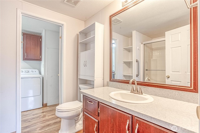 530 Sunday Dr, East Wenatchee, WA 98802 - bathroom featuring washer / dryer, wood finished floors, vanity, a textured ceiling, and a shower with shower door