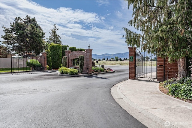 530 Sunday Dr, East Wenatchee, WA 98802 - view of asphalt road with a gate, a mountain view, curbs, and a gated entry
