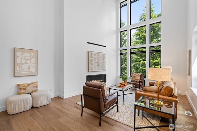 2115 Squak Mountain Loop SW, Issaquah, WA 98027 - living room featuring a high ceiling, healthy amount of natural light, wood finished floors, and a lit fireplace