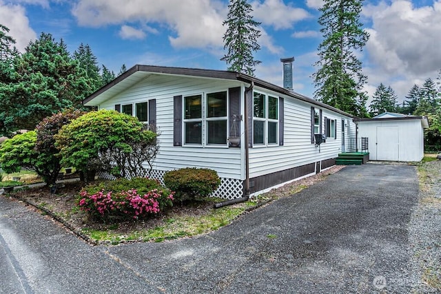 12614 113th Ave E Unit 247, Puyallup, WA 98374 - view of property exterior with a storage shed and asphalt driveway