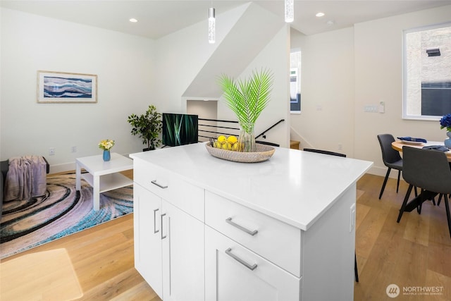 10533 Stone Ave N Unit E, Seattle, WA 98133 - kitchen with light wood finished floors, a kitchen island, light countertops, recessed lighting, and hanging light fixtures