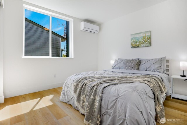 10533 Stone Ave N Unit E, Seattle, WA 98133 - bedroom featuring an AC wall unit and wood finished floors