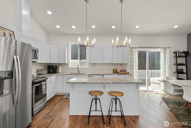 1828 Kristina Ln, Wenatchee, WA 98801 - kitchen featuring stainless steel appliances, a chandelier, a breakfast bar, decorative backsplash, and recessed lighting