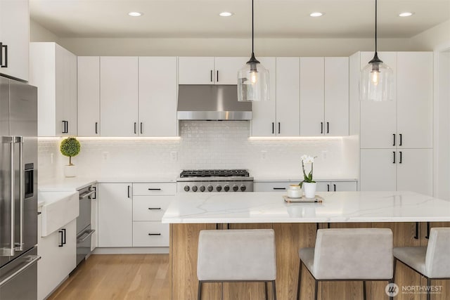 2809 NW 71st St, Seattle, WA 98117 - kitchen with under cabinet range hood, appliances with stainless steel finishes, white cabinetry, light wood-style flooring, and recessed lighting