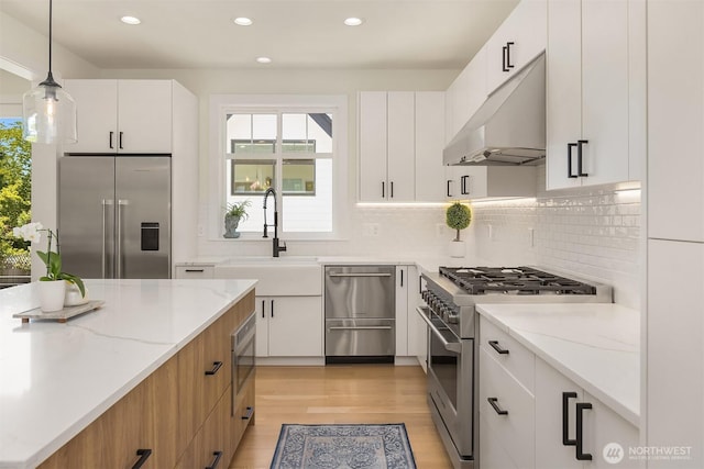 2809 NW 71st St, Seattle, WA 98117 - kitchen featuring high end appliances, under cabinet range hood, recessed lighting, plenty of natural light, and light stone counters