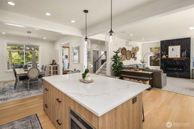 2809 NW 71st St, Seattle, WA 98117 - kitchen featuring light wood-type flooring, a fireplace, modern cabinets, a kitchen island, and light stone counters